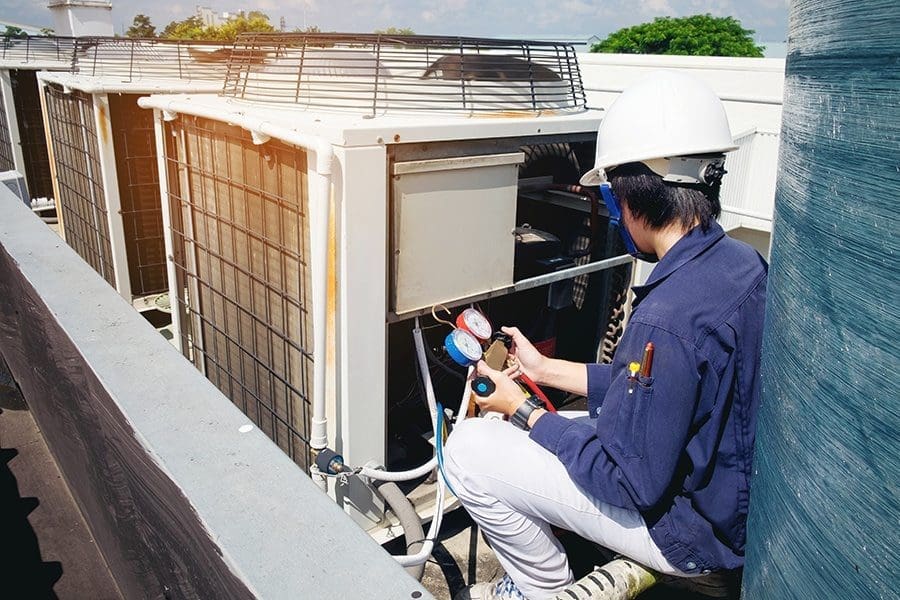 a person wearing safety gears and inspecting hvac system