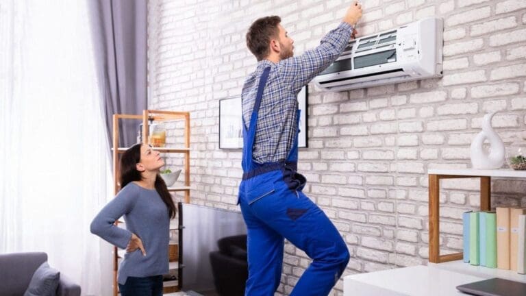 a technician is repairing ac on wall and a girl is standing behind him watching ac repair
