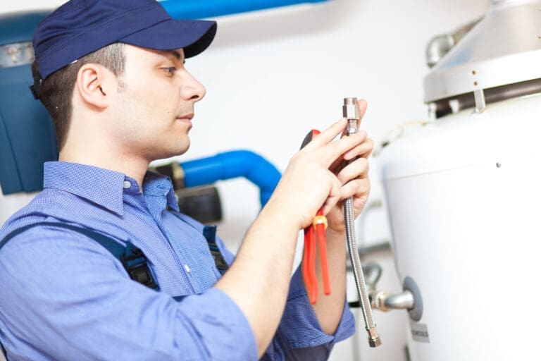 a boiler repair technician inspecting a boiler valve and have plyer in his hand.