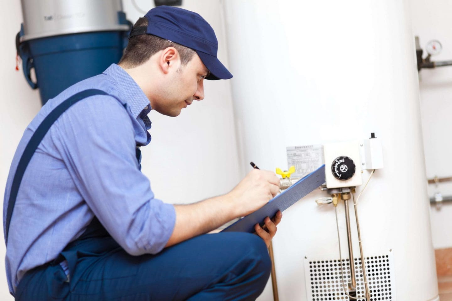 a boiler technician inspecting a boiler and making notes.