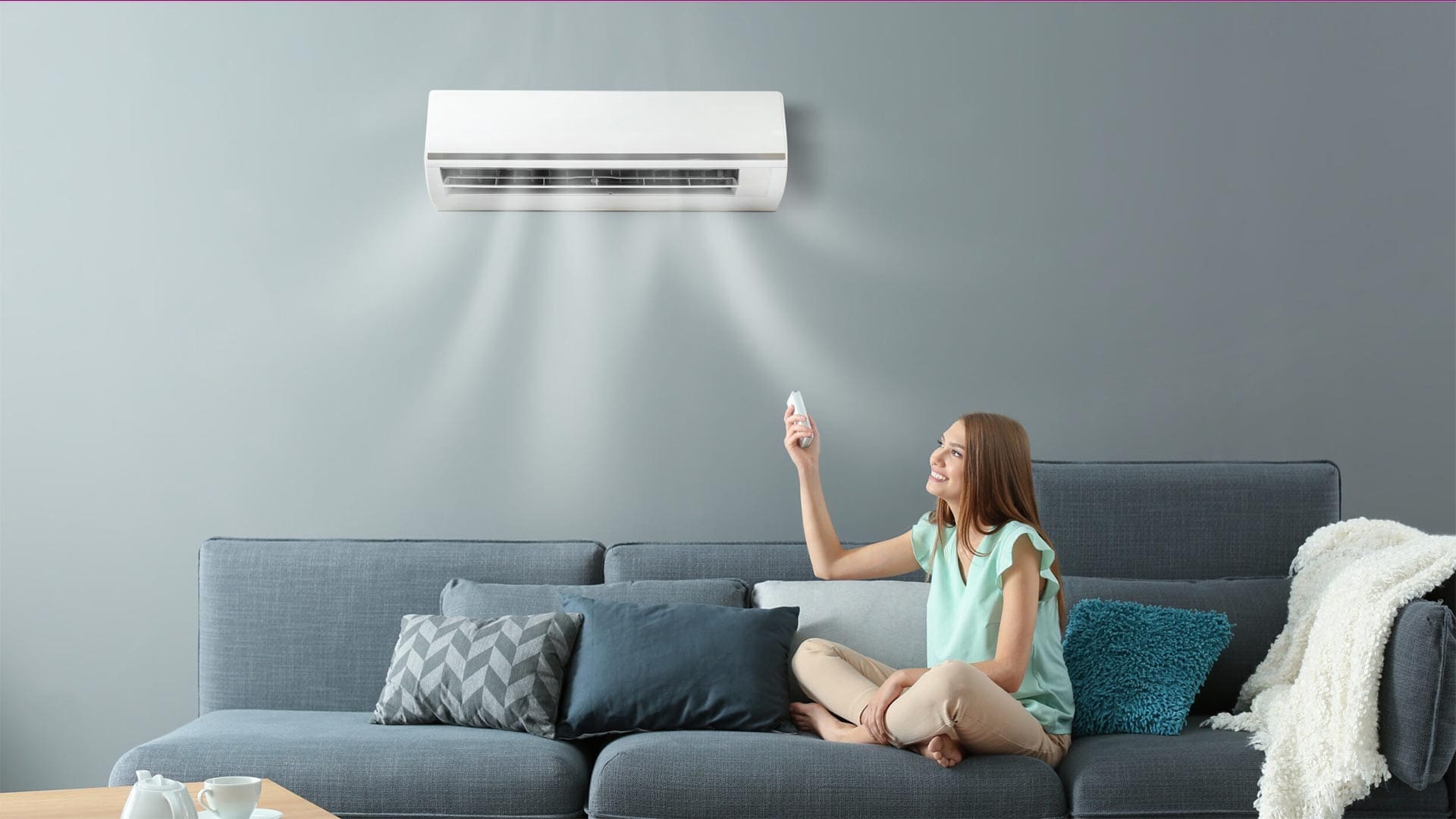a woman sitting on a couch and turning on air conditioner.