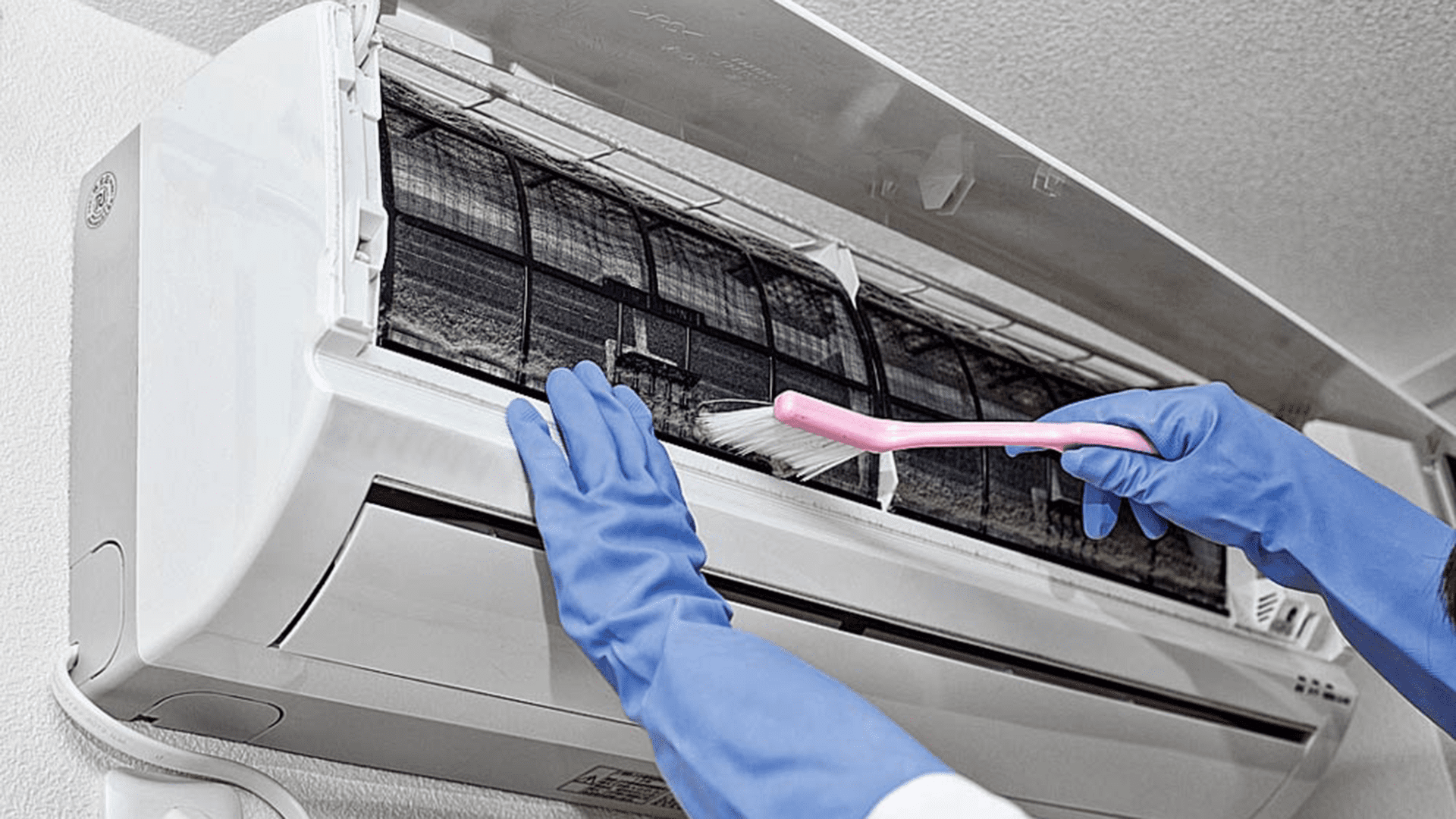 close shot of hands wearing blue gloves cleaning air conditioner's indoor unit air filters.