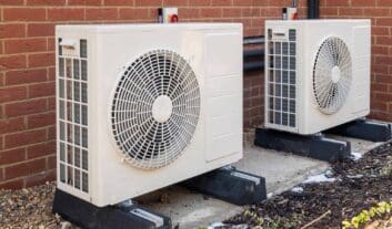 Two,Air,Source,Heat,Pumps,Installed,On,The,Exterior,Of Two air source heat pumps installed on the exterior of a modern house